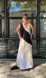 Vestido largo de lino con escote en V, sin mangas, con diseño de paneles diagonales en colores negro, beige y blanco. Presenta costuras vistas y tajos laterales.