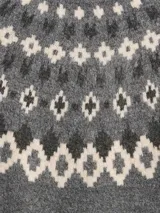 Buzo de punto con cuello alto, diseño estampado estilo fairisle con rayas horizontales y puntos en tonos tostado y blanco. Presenta mangas largas con puños acanalados y ruedo recto.
