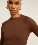 Blusa de manga larga con diseño ajustado, confeccionada en tejido acanalado de viscosa con elastano. Presenta cuello redondo y sisas raglán.