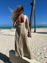 Vestido largo de tirantes, con corpiño en color blanco texturizado y falda larga en tono beige/dorado con brillo sutil. Presenta un escote en V profundo en el frente.