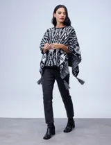 Poncho tejido con diseño tribal en blanco y negro, terminación con borlas.
