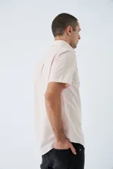 Camisa blanca de manga corta con cuello abotonado (button-down) y bolsillo en el pecho con logo bordado.