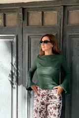 Remera de manga larga con diseño oxford, confeccionada en tejido de algodón acanalado color verde. Presenta un corte ajustado al cuerpo y mangas acampanadas con terminaciones al corte.