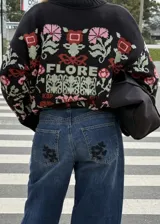 Buzo tejido de algodón negro con diseño jacquard de flores multicolor, cuello en V y mangas largas.