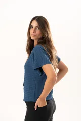 Blusa de silueta relajada y cuello redondo, confeccionada en tela liviana con textura. Presenta mangas cortas y una caída suelta.