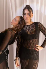 Vestido largo de encaje negro con transparencias, mangas largas y cuello redondo, acompañado de un top y un short interior a juego.