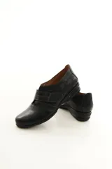 Zapato de cuero negro con cierre de velcro ancho y costuras pespunteadas a contratono.
