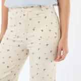 Pantalón de corte wide leg en color crudo con estampado floral pequeño, tiro alto, bolsillos frontales y cierre con botón y cremallera.