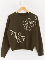 Sweater de punto color marrón chocolate con diseño floral bordado en cordón color crudo. Presenta cuello redondo, mangas largas y puños acanalados.