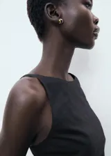 Vestido corto sin mangas de color negro, con cuello barco y diseño drapeado en la cintura. Confeccionado en una mezcla de lino y algodón con forro interior.