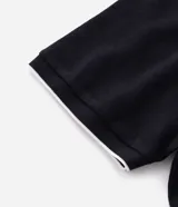 Polo de manga corta confeccionada en algodón de media malla, color negro con detalles en blanco en el cuello y los bordes de las mangas. Presenta cuello polo tradicional y cierre frontal con botones.