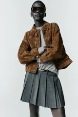 Falda pantalón de tiro alto con diseño de tablas, confeccionada en tejido gris. Incluye un cinturón fino de cuero sintético con hebilla metálica dorada y cierre lateral con cremallera oculta.
