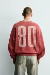 Sudadera de corte boxy fit con cuello redondo y manga larga. Presenta un diseño con efecto lavado y estampado frontal con la palabra Milano en tipografía universitaria a contraste.