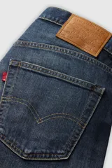 Pantalón de jean azul oscuro, corte slim fit, con pierna cónica y tiro medio. Diseño clásico de cinco bolsillos.