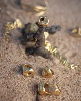 Anillo plateado con forma orgánica irregular y un agujero en el centro.