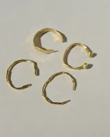 Brazalete rígido abierto de metal color plateado, con terminaciones en forma de herradura.