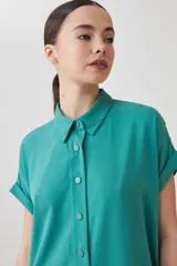 Túnica verde de lyocell con cuello camisero, manga corta con dobladillo y cierre frontal con botones.