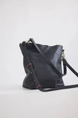 Cartera tipo shopper de cuero color suela, con diseño minimalista, correa larga ajustable y herrajes metálicos en tono bronce.