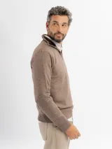 Buzo de tejido de punto color azul con textura jaspeada, cuello alto con cierre frontal parcial y puños acanalados.