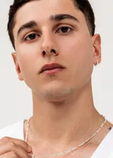 Par de aros tipo argolla pequeños de plata 925, con diseño trenzado o retorcido incrustado con pequeñas circonias brillantes.