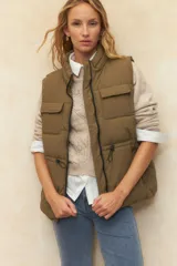 Chaleco puffer color verde militar, con cuello alto, cierre frontal y cuatro bolsillos con solapa.