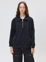 Buzo verde militar de algodón suave, de calce oversize, con cuello alto y cierre frontal parcial metalizado. Cuenta con bolsillos laterales con cierre y puños y ruedo elastizados.