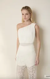 Top blanco de un solo hombro con detalle de volados y corte a la cintura.