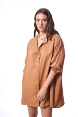 Vestido camisero color marrón claro, de corte oversized, manga 3/4 con puños elásticos y cierre frontal con botones a tono.