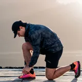 Campera cortaviento con capucha, estampado camuflado en tonos grises y logo Merrell en el pecho. Cierre frontal con cremallera y bolsillos laterales. Ideal para trail running.