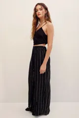 Pantalón fluido de tiro medio con diseño de rayas verticales metalizadas en tono dorado sobre base negra, corte amplio y silueta recta.