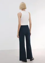 Pantalón azul marino de tiro medio y corte flare, con bolsillos frontales decorados con botones dorados.