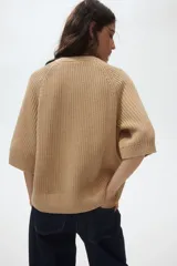 Buzo de punto suave con cuello redondo, mangas raglán al codo y corte holgado. Presenta terminaciones acanaladas en cuello, mangas y bajo.