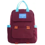 Mochila urbana de color bordó con detalles en celeste y naranja. Cuenta con un compartimento principal con solapa, un bolsillo frontal, asas superiores y correas ajustables. Incluye un parche decorativo con la frase 'You are the best version of yourself'.