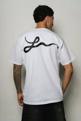 Remera blanca de algodón, corte regular fit, con un pequeño estampado ovalado en el pecho y un gran estampado de firma estilizada en la espalda.