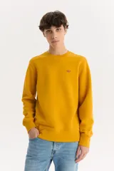 Buzo de algodón color mostaza, de corte clásico con cuello redondo y logo de la marca bordado en el pecho.