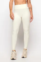 Calza larga deportiva de tiro alto en color marfil, confeccionada en tejido elástico con costuras drapeadas que realzan la figura.