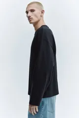 Remera de manga larga en punto pesado, con cuello redondo, hombros caídos y corte oversized.