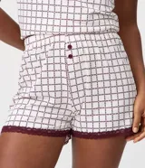Short de pijama femenino confeccionado en tejido peach touch de poliéster, con cintura elastizada, botones frontales y encaje bordó en los bajos. Presenta un estampado geométrico con pequeños corazones en tonos blancos y oscuros.