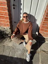 Buzo marrón de algodón, corte holgado, con cuello redondo y puños ajustados.