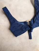 Top de bikini con acabado brillante color verde militar, escote redondo y argolla de madera decorativa en el centro.