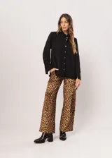 Camisa negra de cuello redondo con frunces y mangas largas con puños abiertos.