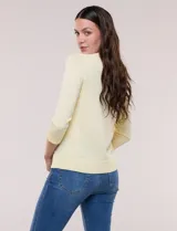 Cardigan de punto fino color amarillo con escote a la base, mangas tres cuartos y abotonadura frontal con botones metálicos decorativos.