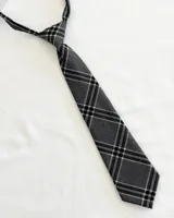 Corbata infantil gris oscuro con diseño de cuadrillé en blanco y negro, con elástico ajustable.