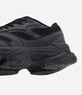 Championes estilo dad sneaker de diseño robusto, color negro, con suela alta y recortes laterales. Presentan cierre mediante cordones y una estructura que combina paneles de malla y material sintético.