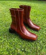 Bota corta de cuero color bordó, con punta cuadrada y taco bloque bajo. Cierre lateral con cremallera.