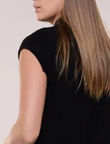Chaleco de punto waffle color negro, sin mangas, con cuello alto, cierre frontal de botones metálicos dorados y bolsillos frontales aplicados.