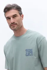 Remera de manga corta color azul marino con cuello redondo y calce regular. Presenta un estampado artístico en la espalda con diseño floral estilizado y tipografía.