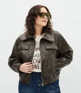 Campera bomber de cuero sintético color verde oliva, con cuello inglés, cierre frontal con cremallera, bolsillos laterales y bolsillos frontales con solapa.