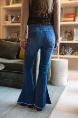 Jean de denim azul de corte acampanado, con costuras frontales en relieve tipo alforza y terminación desmechada en el bajo.