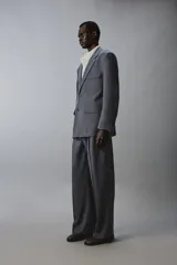 Pantalón de traje con corte flare fit, confeccionado en tejido con lana. Presenta diseño de tiro medio con pinzas frontales, bolsillos laterales y bolsillos traseros de vivo. Cierre frontal con cremallera y botón.